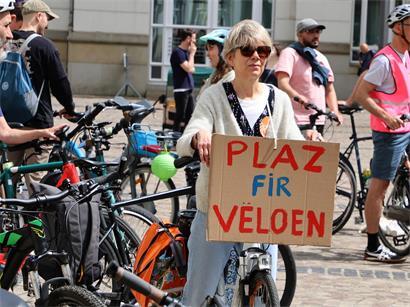 Demonstrantin hält Schild mit Schriftzug „Platz für Fahrräder“ bei einer Fahrrad-Demonstration im urbanen Umfeld