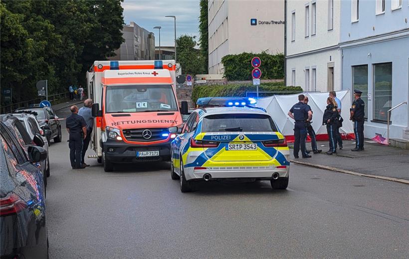 Polizei und Rettungskräfte sind neben einem Sichtschutz im Einsatz. In Passau ist ein Mann mit einem Wagen in eine Menschengruppe gefahren. Die Polizei schloss nicht aus, dass er das Fahrzeug bewusst in die Menschengruppe gelenkt hat. 
