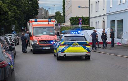 Polizei und Rettungskräfte sind neben einem Sichtschutz im Einsatz. In Passau ist ein Mann mit einem Wagen in eine Menschengruppe gefahren. Die Polizei schloss nicht aus, dass er das Fahrzeug bewusst in die Menschengruppe gelenkt hat. 
