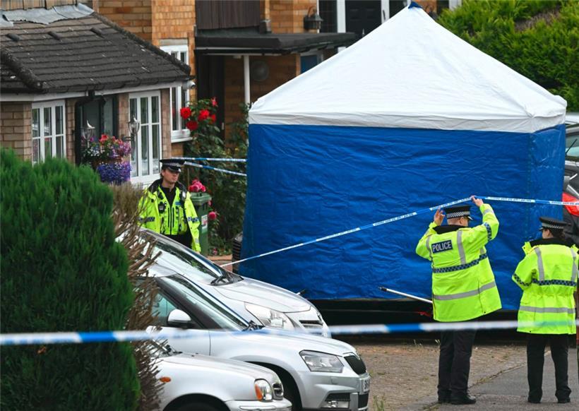 Polizeibeamte stehen nach einem dreifachen Armbrustangriff in Ashley Close, nördlich von London, vor einem Zelt der Spurensicherung Wache
