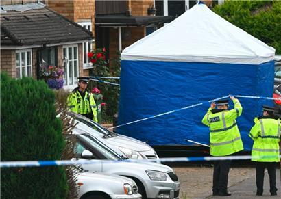Polizeibeamte stehen nach einem dreifachen Armbrustangriff in Ashley Close, nördlich von London, vor einem Zelt der Spurensicherung Wache
