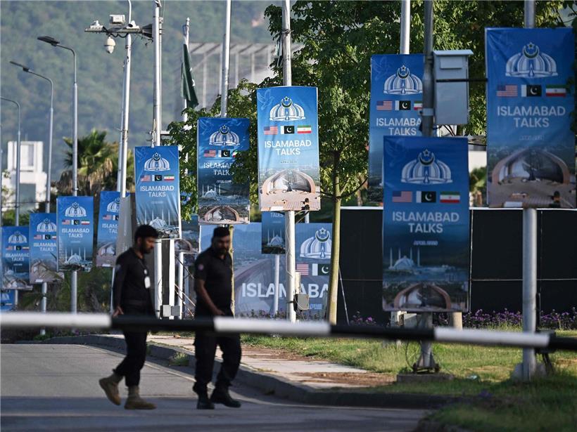 Polizisten patrouillieren am 25. April 2026 nahe Serena Hotel im Red Zone Viertel von Islamabad an Plakaten vorbei