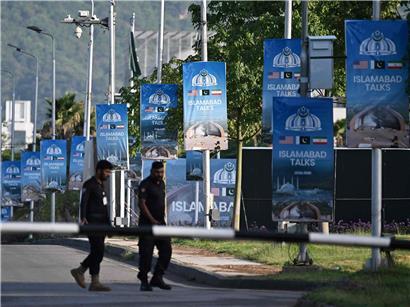 Polizisten patrouillieren am 25. April 2026 nahe Serena Hotel im Red Zone Viertel von Islamabad an Plakaten vorbei