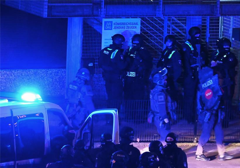 Polizisten sind in Hamburg im Einsatz und stehen vor einem Schild mit der Aufschrift „Königreichssaal Jehovas Zeugen“
