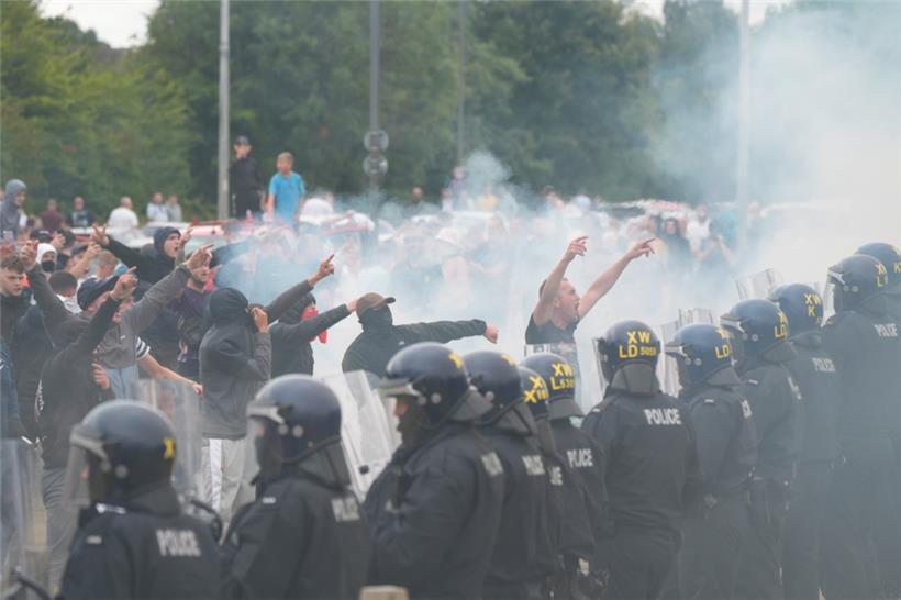 Polizisten stehen vor Randalierern bei gewalttätigen Auseinandersetzungen auf einer Anti-Einwanderungsdemonstration vor dem Holiday Inn Express Hotel, in dem Asylbewerber untergebracht sind
