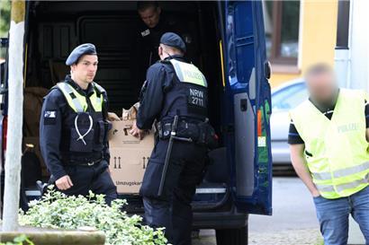 Polizisten tragen Gegenstände aus dem Wohnhaus des Verdächtigen. Die Polizei in Essen ermittelt wegen möglicherweise geplanter Straftaten an zwei Schulen gegen einen 16-Jährigen. 
