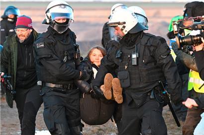 Polizisten tragen die schwedische Klimaaktivistin Greta Thunberg (M) aus einer Gruppe von Demonstranten und Aktivisten heraus und vom Rand des Braunkohlentagebaus Garzweiler II weg
