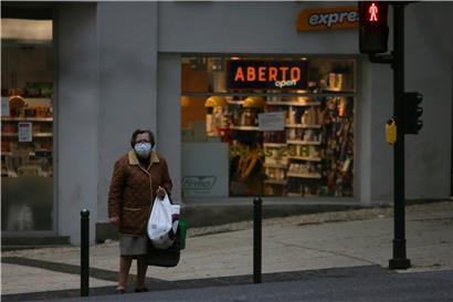 Portugal, Lissabon: Eine Frau mit Mundschutz trägt ihre Einkäufe aus einem Supermarkt.
