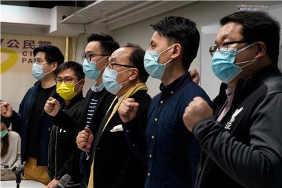 Pro-demokratische Parteimitglieder tragen Mund-Nasen-Schutz und rufen Parolen während einer Pressekonferenz in Hongkong. Rund 50 pro-demokratische Aktivisten und frühere Abgeordnete sind in der Stadt wegen angeblicher Verstöße gegen das neue Sicherheitsgesetz festgenommen worden.
