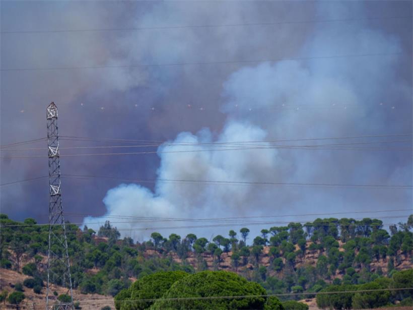Rauch steigt hinter einer Bergkuppe mit einem Strommast auf. Der Waldbrand, der am vergangenen Donnerstag in Niebla (Huelva) ausgebrochen ist, hat sich mittlerweile auf 8.000 Hektar ausgebreitet und zur Evakuierung von 474 Menschen geführt.