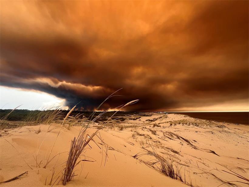 Rauchwolken von den Waldbränden südöstlich des Badeortes Lacanau-Ocean (hinten, r) verdunkeln den Himmel, während sie über die Dünen am Nordstrand hinwegziehen.