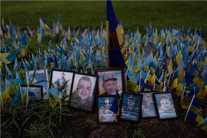 Regentropfen liegen auf Fotos von ukrainischen Soldaten, die im Krieg Russlands gegen die Ukraine gefallen sind, an einer Gedenkstätte zu Ehren der gefallenen Soldaten nahe Kiew
