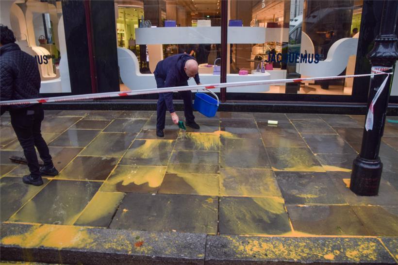 Reinigungskräfte waschen Farbe ab. Die Umweltaktivisten der Gruppe „Just Stop Oil“ haben in den vergangenen Wochen mehrere Aktionen durchgeführt. Unter anderem hier vor dem berühmten Kaufhaus in Knightsbridge am 20. Oktober. 
