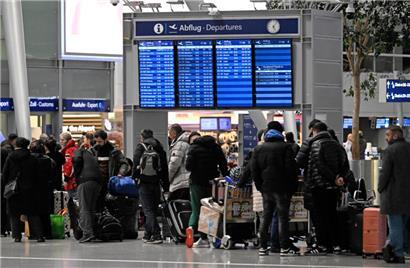 Reisende bilden am Flughafen Düsseldorf beim Check-in eine Schlange
