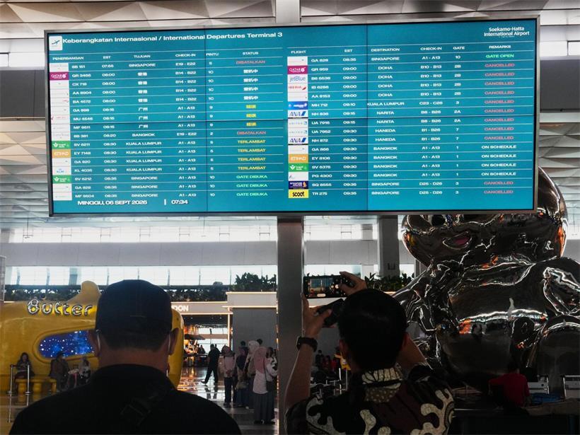 Reisende gehen am internationalen Flughafen Soekarno-Hatta an einer Informationstafel vorbei, auf der Flugausfälle angezeigt werden