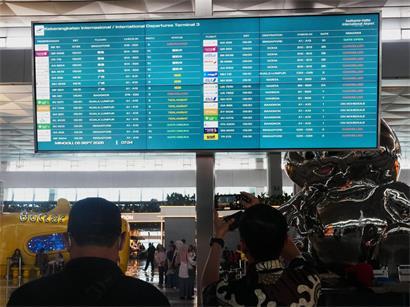 Reisende gehen am internationalen Flughafen Soekarno-Hatta an einer Informationstafel vorbei, auf der Flugausfälle angezeigt werden