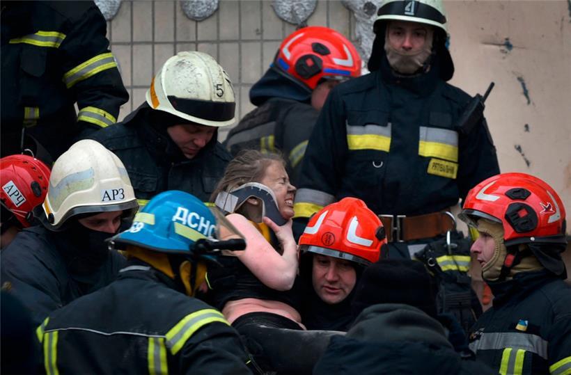Retter tragen eine Frau aus den Trümmern des nach einem Raketeneinschlag zerstörten Wohnhauses in Dnipro
