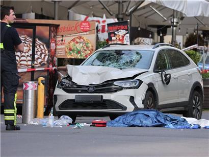 Rettungskräfte am Unfallort mit beschädigtem Auto nach Fahrzeug prallt in Menschenmenge
