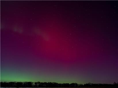 Nachthimmel über Deutschland in roten und grünen Farbtönen mit leuchtenden Nordlichtern und Sternenhimmel