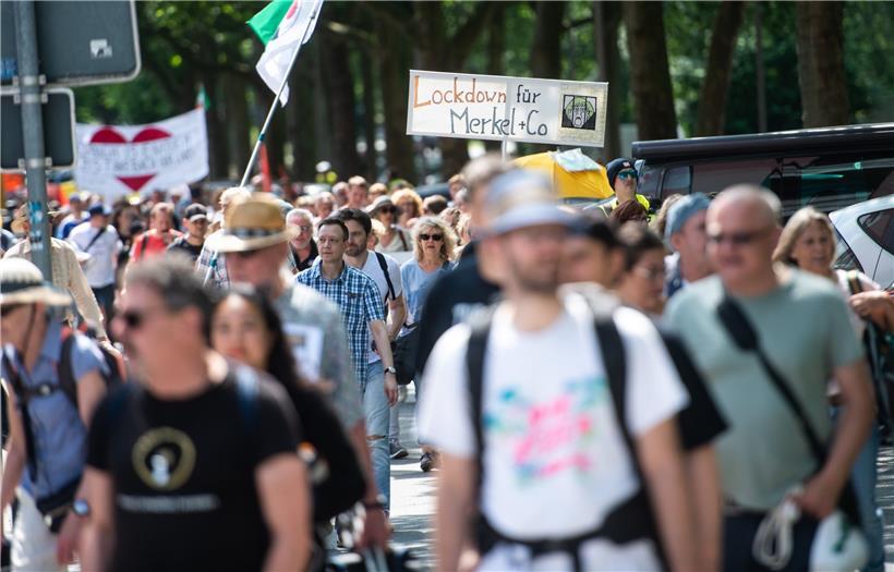 Rund 500 sogenannte Querdenker ziehen Anfang Juli in Bochum in einem Protestmarsch aus der Innenstadt zum Veranstaltungsgelände auf dem Kirmesplatz und tragen dabei ein Schild mit der Aufschrift „Lockdown für Merkel + Co“
