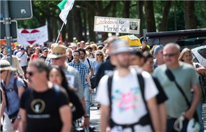 Rund 500 sogenannte Querdenker ziehen Anfang Juli in Bochum in einem Protestmarsch aus der Innenstadt zum Veranstaltungsgelände auf dem Kirmesplatz und tragen dabei ein Schild mit der Aufschrift „Lockdown für Merkel + Co“
