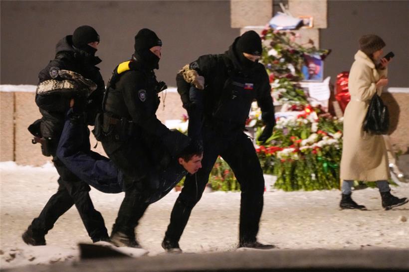Russland, St. Petersburg: Polizeibeamte halten einen Mann fest, der Blumen zu Ehren von Alexej Nawalny an einem Denkmal für die Opfer der sowjetischen Unterdrückung in St. Petersburg, Russland, niedergelegt hat
