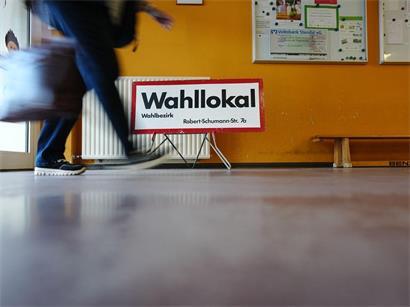 Sachsen-Anhalt, Tangermünde: Eine Wahlhelferin geht am frühen Morgen in einem Wahllokal in Tangermünde an dem Schild „Wahllokal“ vorbei