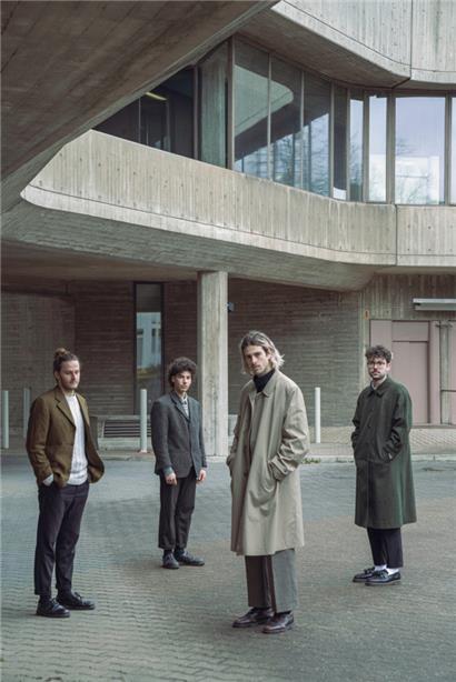 Sam Tritz (Gesang, Gitarre), Yann Gengler (Bassgitarre), Tun Biever (Gesang, Gitarre) und Tom Zuang (Schlagzeug) vor dem Bürogebäude von „Reality Management Ltd.“
