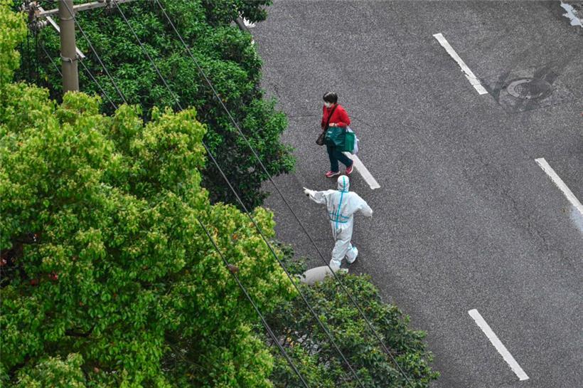 Schanghai im Lockdown: Ein Beamter in Schutzausrüstung gibt einer Frau Anweisungen 
