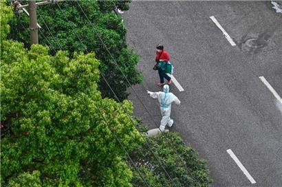 Schanghai im Lockdown: Ein Beamter in Schutzausrüstung gibt einer Frau Anweisungen 
