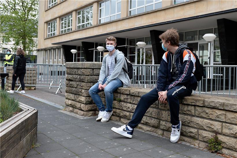 Schüler sitzen mit Sicherheitsabstand und Maske auf der Mauer vor ihrer Schule. In manchen Fällen halten sich die Jugendlichen aber nach Schulschluss nicht mehr an die Bestimmungen, sagt die Elternvertretung. 
