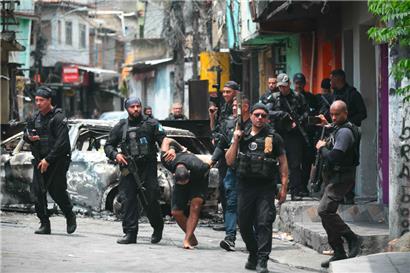 Schwer bewaffnete Beamte der „Operação Contenção“ führen einen Verhafteten aus dem Complexo de Penha in Rio de Janeiro ab
