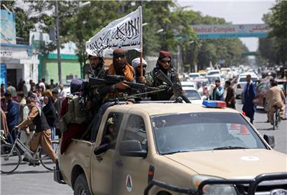 Schwer bewaffnete Taliban-Kämpfer patrouillieren nach ihrer Machtübernahme mit wehender Fahne des Islamischen Emirats Afghanistan durch Kabul in Afghanistan
