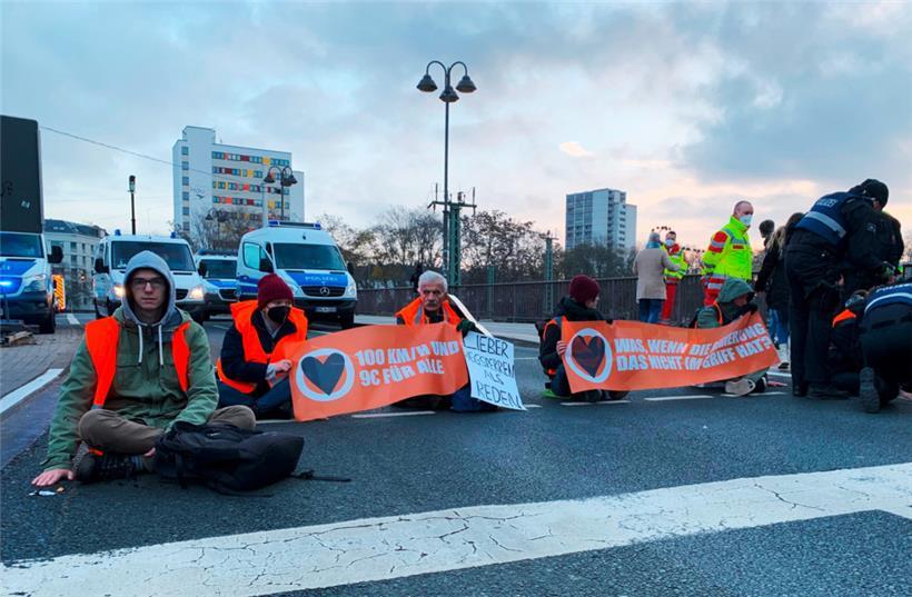  Sechs Aktivisten der Gruppe „Letzte Generation“ haben sich auf einer mehrspurigen Straße am Hauptbahnhof in Mainz mit einer Hand auf dem Asphalt festgeklebt
