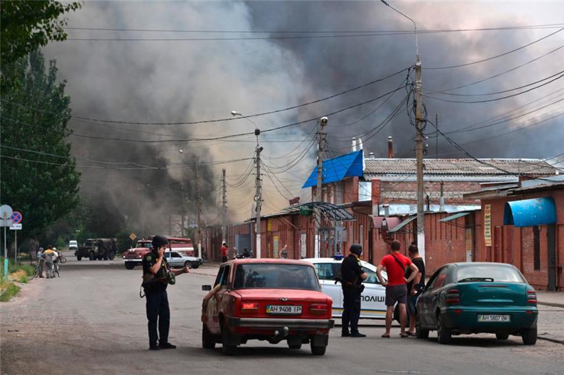 Sicherheitskräfte halten Autofahrer an, als nach einem mutmaßlichen russischen Raketenangriff Rauch aus dem zentralen Markt von Sloviansk nördlich von Kramatosk aufsteigt
