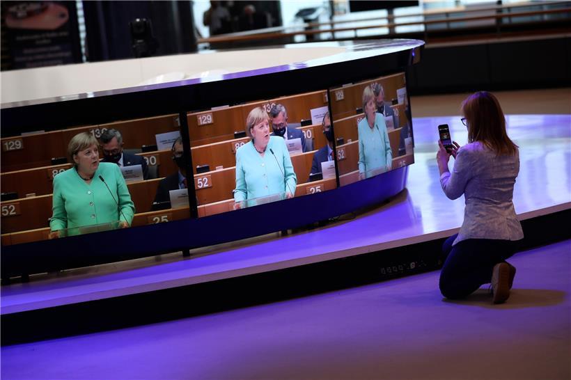 Social Distancing bei der Programmvorstellung in Brüssel: Eine Frau filmt einen Bildschirm, der die deutsche Kanzlerin Angela Merkel bei ihrer Rede zur Ratspräsidentschaft an das Plenum im Europäischen Parlament zeigt
