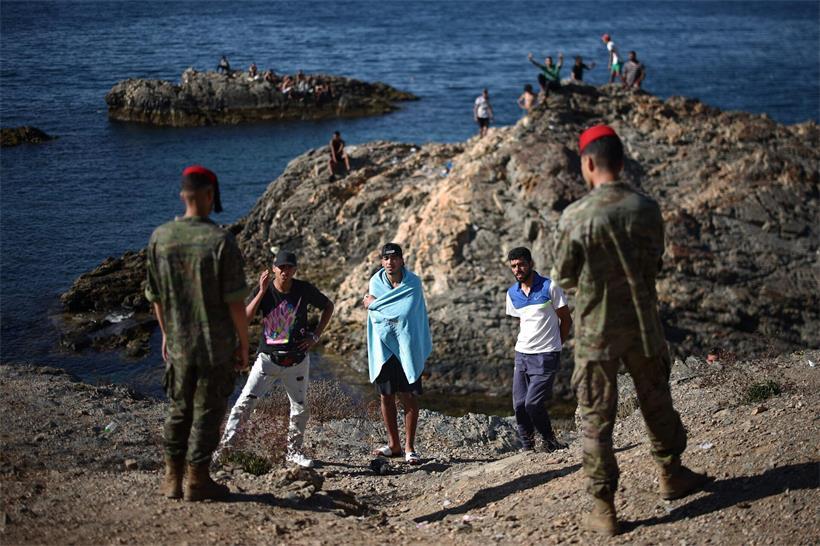 Soldaten der spanischen Armee und drei Migranten in der Nähe des Grenzpostens von Ceuta