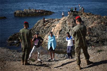 Soldaten der spanischen Armee und drei Migranten in der Nähe des Grenzpostens von Ceuta