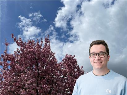 Grau bewölkter Himmel mit leuchtenden rosa Kirschblüten als Farbtupfer im Frühling