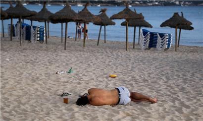 Spanien, Palma: Ein Mann schläft am Strand des Ballermanns auf Mallorca
