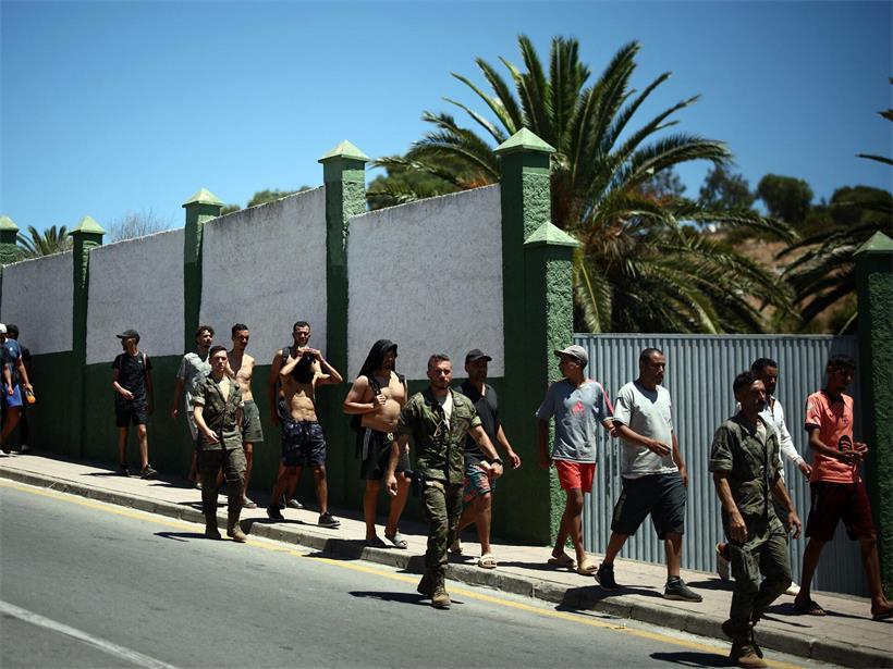 Spanische Soldaten begleiten eine Gruppe irregulärer Migranten in Ceuta an die Grenze zu Marokko