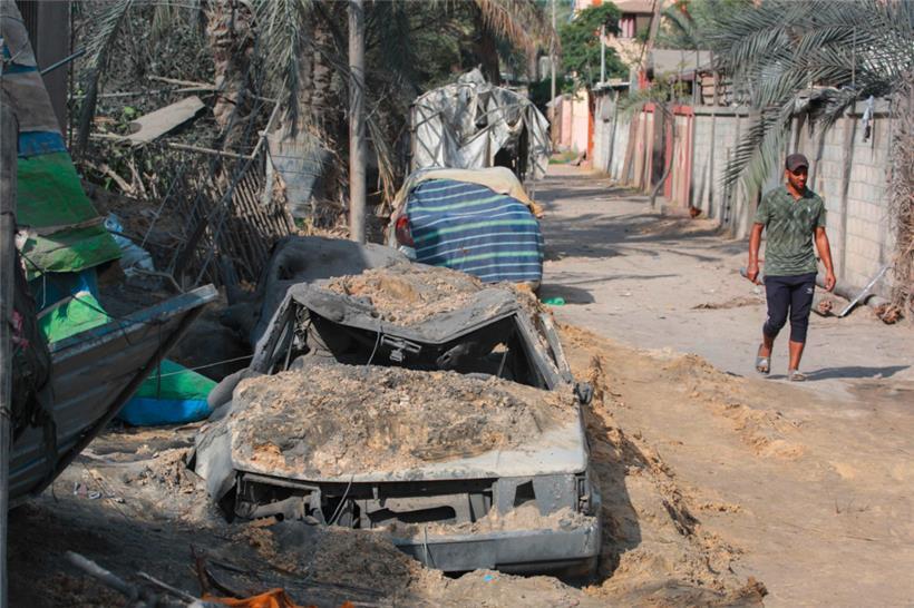 Spuren des Bombardements des Al-Mawasi-Flüchtlingslagers: Ein Mann geht an einem Autowrack vorbei
