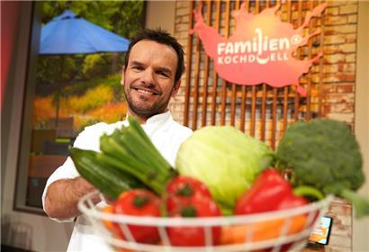 Steffen Henssler, fernseherfahrener Koch, steht in der Studiokulisse der Sendung „Familien-Kochduell“
