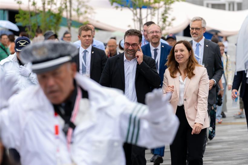Stéphanie Obertin beim Rundgang über die Weltausstellung in Begleitung von Daniel Sahr, dem Direktor des Luxemburger Pavillon. Im Vordergrund ein Sicherheitsbeamter, der den VIP-Gästen den Weg freimacht.
