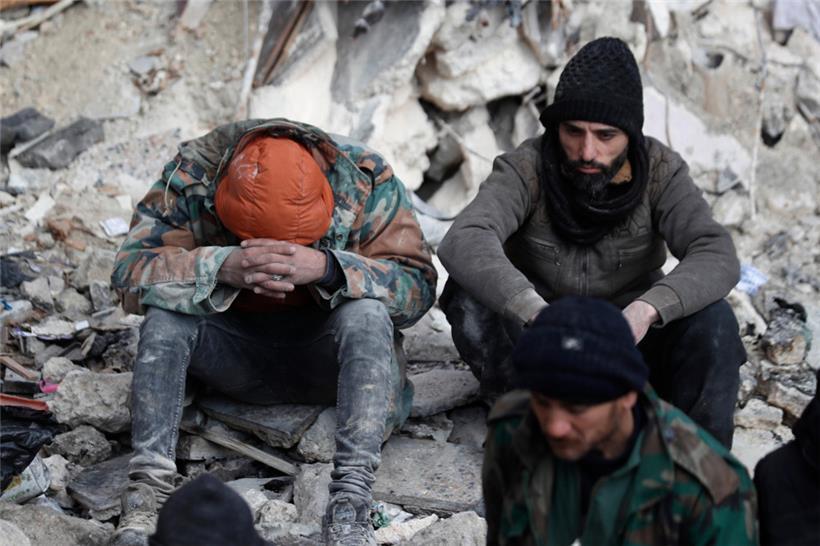 Syrien, Aleppo: Menschen sitzen auf den Trümmern eingestürzter Gebäude
