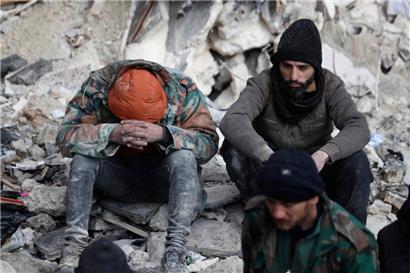 Syrien, Aleppo: Menschen sitzen auf den Trümmern eingestürzter Gebäude
