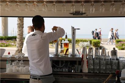 Thiago, ein Kellner, arbeitet in einer Terrassenbar am Strand von Arena auf Mallorca – ab jetzt ohne Maske und weiterhin ohne Zigarettenqualm
