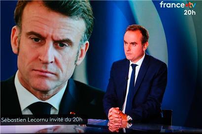 This photograph shows a television screen displaying France’s outgoing Prime Minister Sebastien Lecornu (R), with an image of France’s President Emmanuel Macron in the background, during a live broadcast interview on a set of French TV France 2 in Paris on October 8, 2025. (Photo by Ludovic MARIN / AFP)
