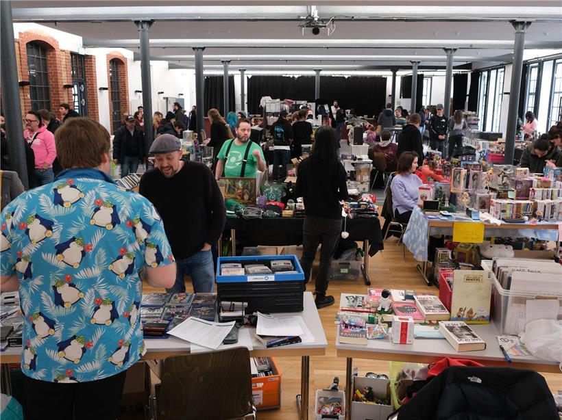 Tische voller Retro-Konsolen, Sammelfiguren und Karten im Geek Floumaart der Schungfabrik, Ort für nachhaltiges Weitergeben