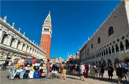 Touristen stehen auf dem Markusplatz mit Campanile (M) und Dogenpalast (r)

